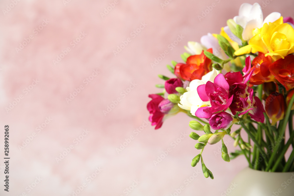 Bouquet of beautiful spring freesia flowers in vase on color background, space for text