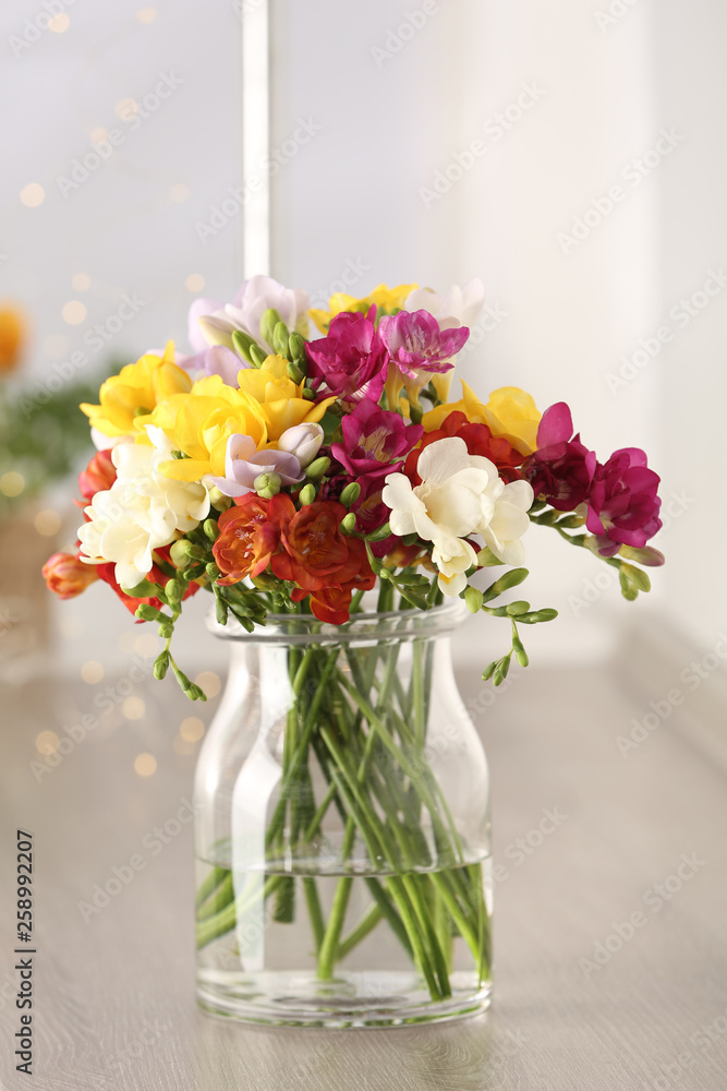 Fototapeta premium Beautiful spring bright freesia flowers in vase on table
