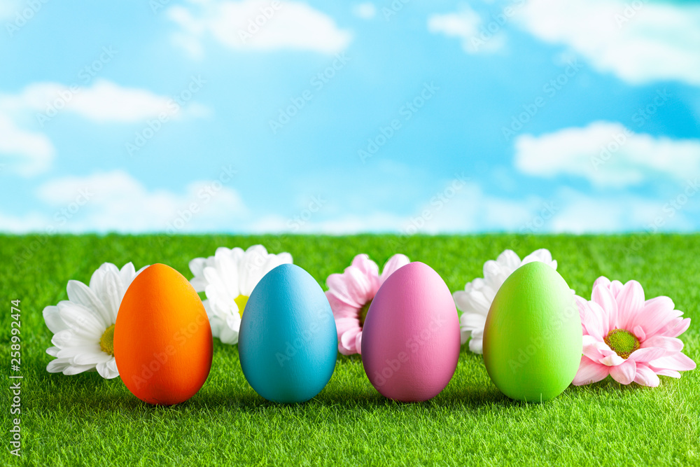 Easter eggs and flowers on the grass and blue sky background Easter eggs and flowers on the grass and blue sky background