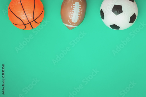 Soccer footbal, rugby and basketball concept with balls on green background. Sports education and tournament for children. Flat lay with copy space