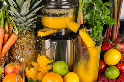 slow juicer in kitchen with many fruit and vegetable orange vitamin juice healthy lifestyle concept background photo