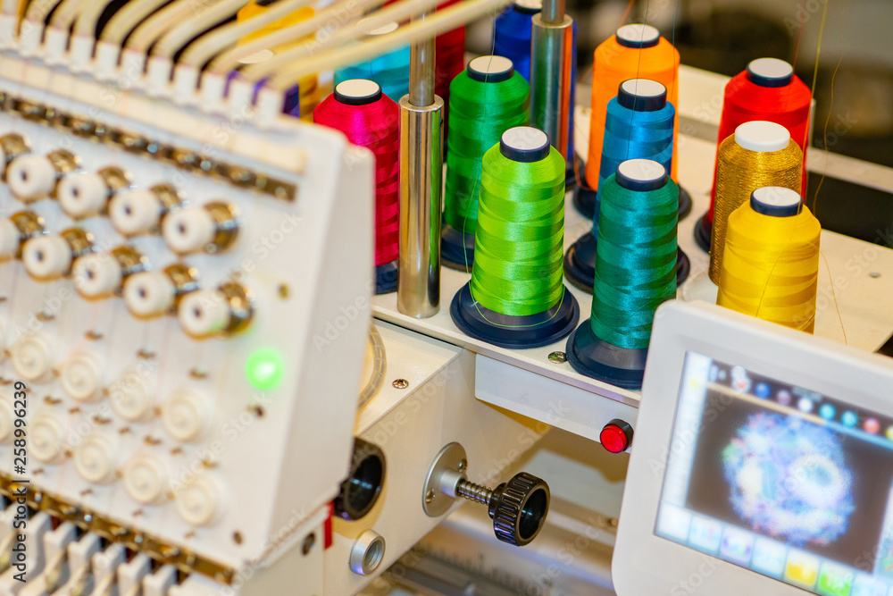 Spools of thread on the embroidery machine. Computer embroidery machine. Industrial embroidery equipment. Programmable embroidery machine. Embroidery patterns.