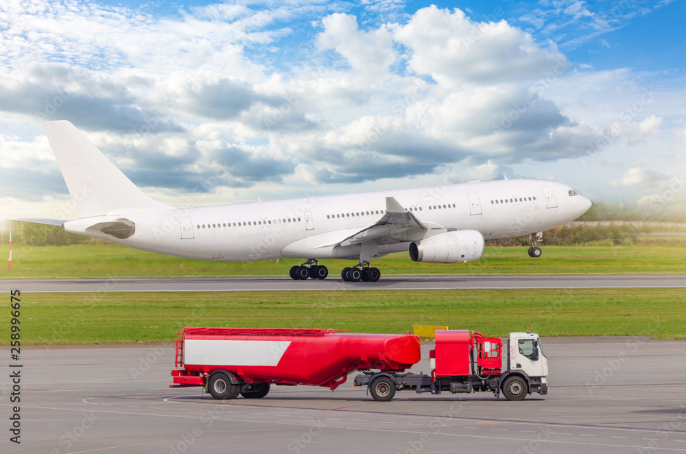 Airplane take off from the runway at the airport, in the foreground a truck with an aviation fuel tank. Airplane take off from the runway at the airport, in the foreground a truck with an aviation fuel tank.