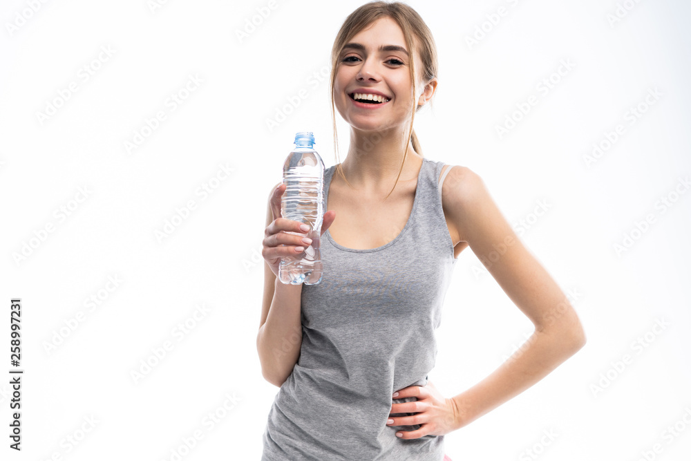 Female fitness model holding a water bottle in a white studio environment. Female fitness model holding a water bottle in a white studio environment.