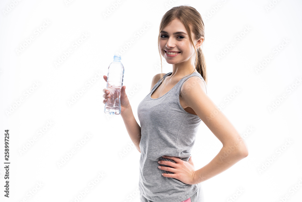 Female fitness model holding a water bottle in a white studio environment. Female fitness model holding a water bottle in a white studio environment.