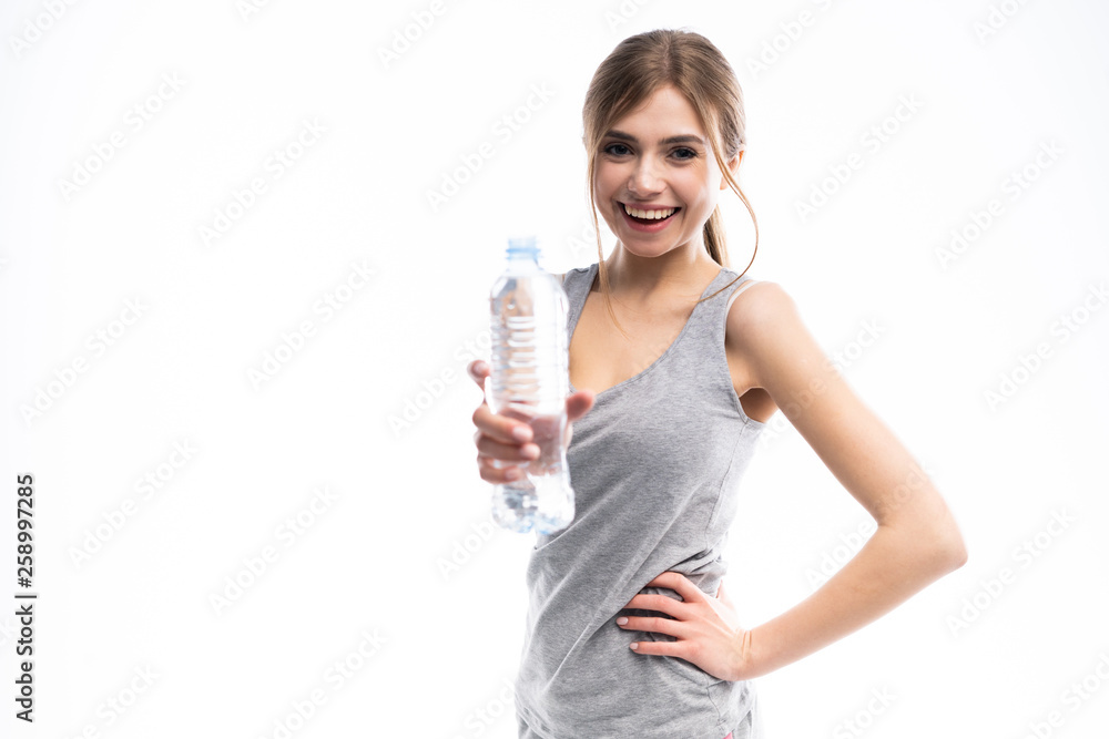 Female fitness model holding a water bottle in a white studio environment. Female fitness model holding a water bottle in a white studio environment.