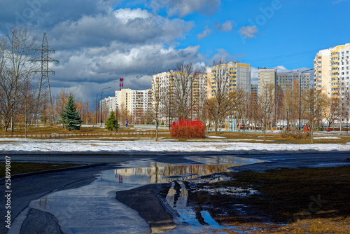 Photography Urban houses and sky with clouds reflected in puddle from melting snow on street