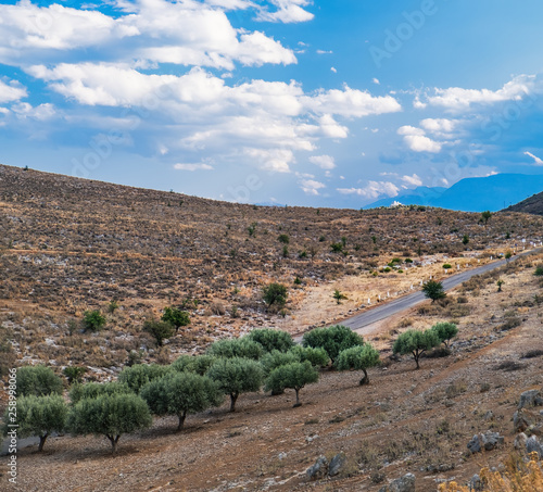 Panoramic landscape with asphalt road and mountains over blue cloudy sky in Western Greece