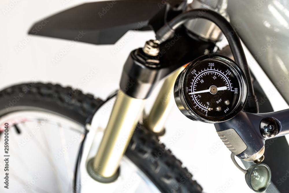 Fototapeta premium Pumping the bicycle wheel using a hand pump with air pressure indicator in units of bar / psi.