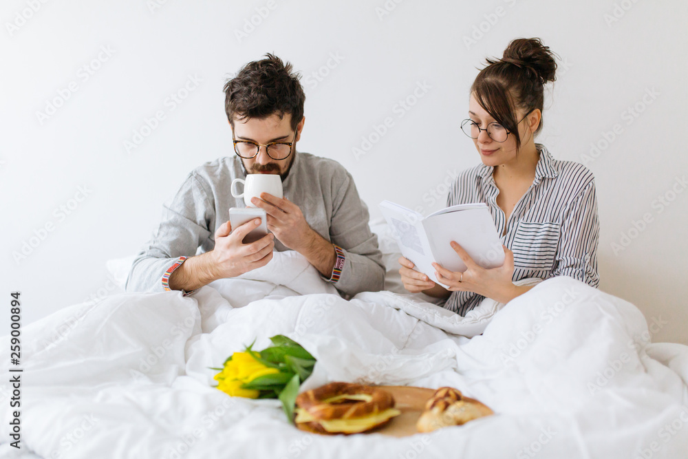 Young couple in bed having breakfast