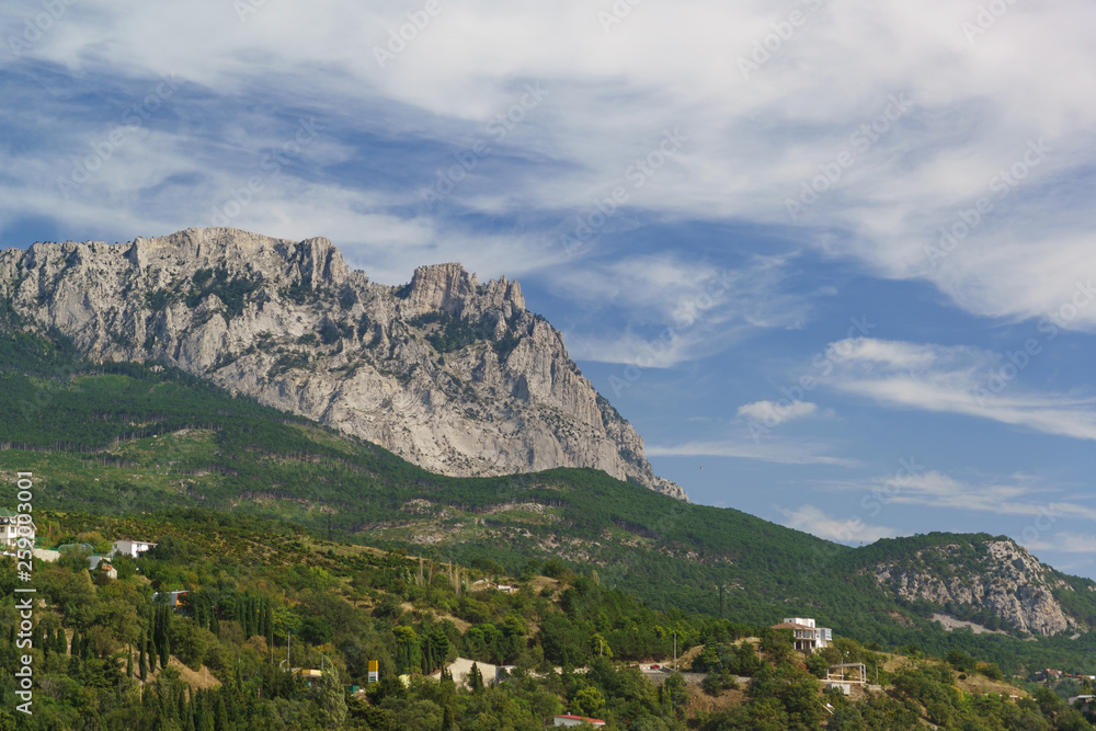 View of the teeth of the Crimean mountain top AI-Petri. Low-rise residential buildings are covered with lush southern greenery. Crimea, Alupka