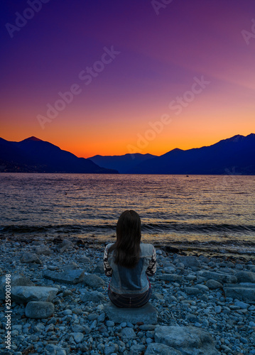 A traveller enjoying violet sunset in the port of Ascona, Switzerland