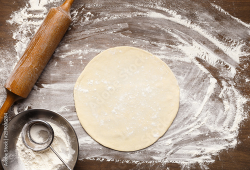 Raw pizza base. Rolled out dough on floured surface photo