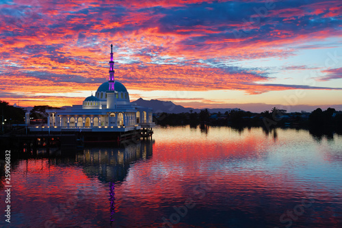 Scenic view of floating mosque on Sarawak river with colorful sunset clouds background. Waterfront landmark in Kota Kuching. Traditional culture and travel destinations on Borneo island in Malaysia.