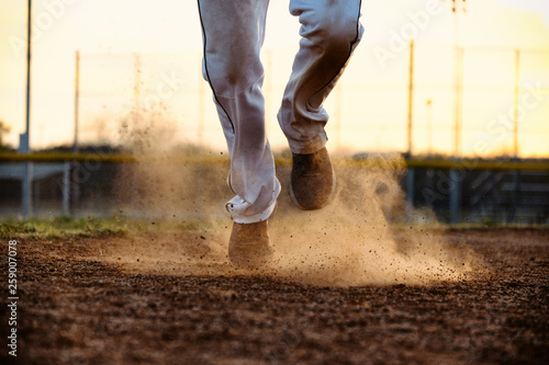 Photography Baseball player feet running to base on field, dirt and dust moving from action of athlete