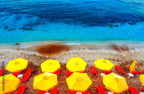 Sun chairs and umbrellas top view on multicolor red white sand sand beach in Crete, Greece photo