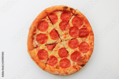 Pepperoni pizza sliced round italian food close up top view isolated on empty white background. Fresh classic pepperoni pizza recipe of hot pizza with fresh pepperoni sausage and cheese ingredients