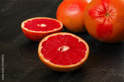 Detail of red grapefruit one citrus halved, on black slate like board