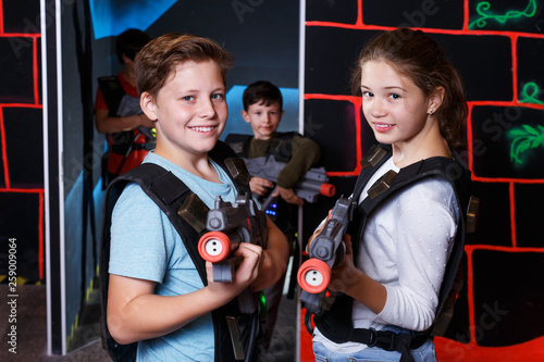 excited teen boy and girl aiming laser gun at other players