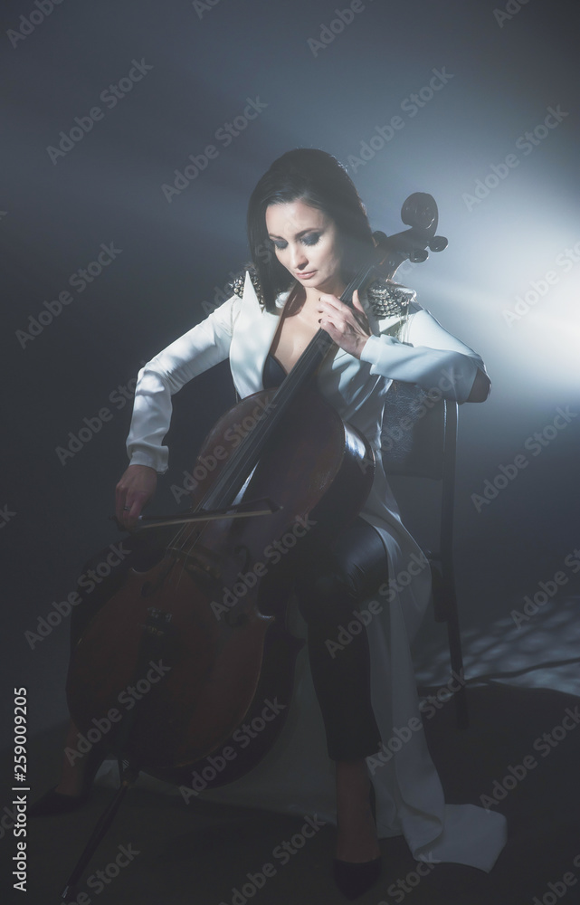 Beautiful woman in a white coat plays the cello Beautiful woman in a white coat plays the cello
