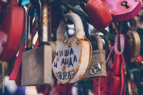 Close up of a love lock on a railing on a locks bridge with other locks blurred to create a bokeh background.