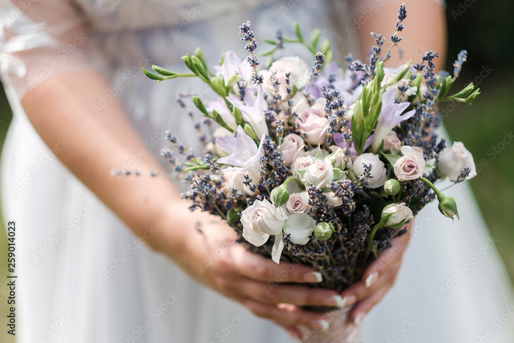Lavender bridal bouquet in the hands of the girl against the backdrop of nature. Lavender bridal bouquet in the hands of the girl against the backdrop of nature.