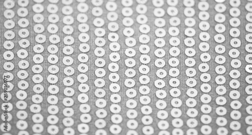 Pale light gray knitted fabric with sequins. Background for wallpaper and other elements of your design with selective Focus.