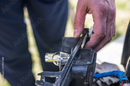 A close-up of an open-headed vehicle lighthouse. Selective focus in defocuses man with his hand on the dusty box.