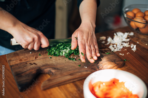 Fotografie Chef chopping parsley with knife on a wooden board