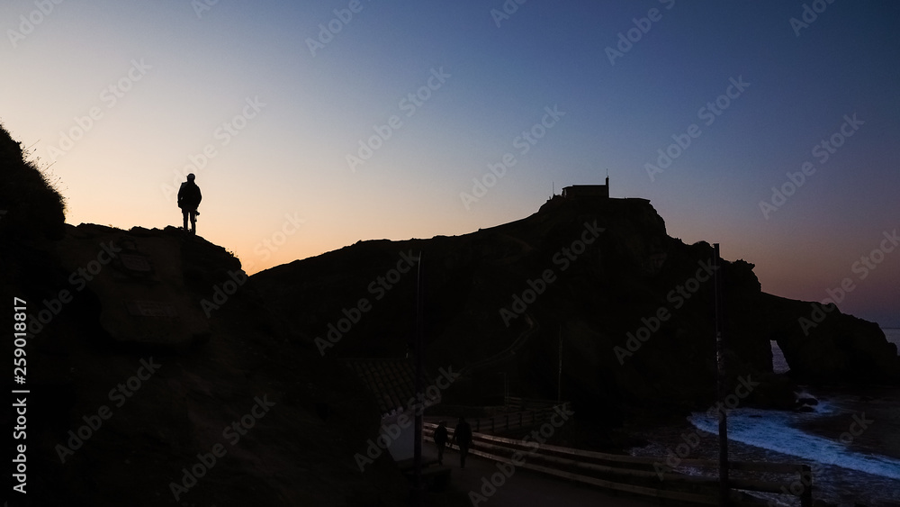 Views of the surroundings of San Juan de Gaztelugatxe during sunset, man's silhouette