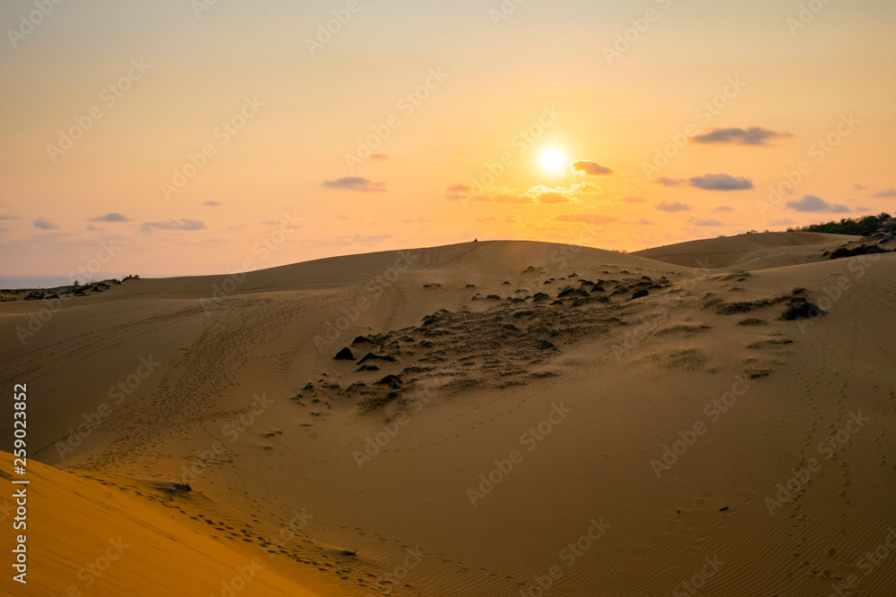 The sun sets over red sand dunes at M?i Né, Vietnam The sun sets over red sand dunes at M?i Né, Vietnam
