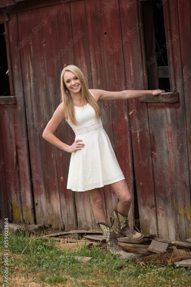 Beautiful young woman playfully posing against old wooden red barn Beautiful young woman playfully posing against old wooden red barn