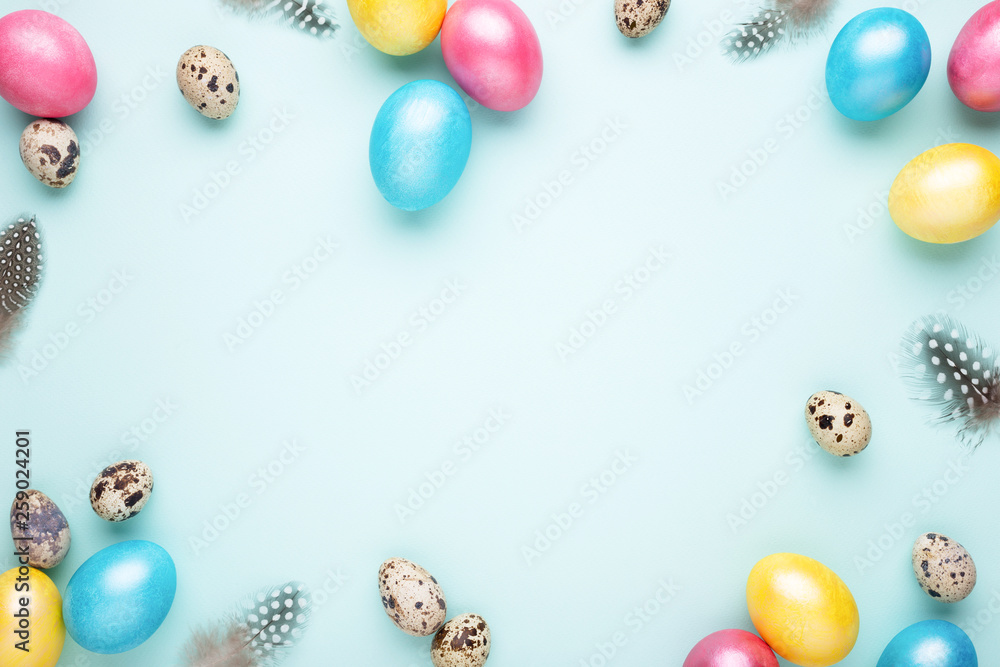 Frame made of colorful Easter eggs on turquoise background. Top view, copy spase, minimal styled.