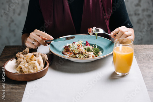 Woman eating tasty salad in restaurant