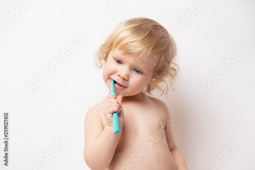 little cute curly baby smiles and cleans teeth on white background