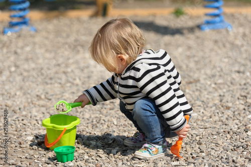 Cute toddler baby girl playing with shovel at playground photo