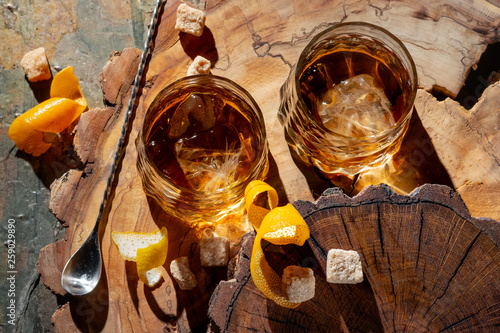 Cocktail with whiskey and orange. Old Fashioned recipe ingredients on wooden board background.