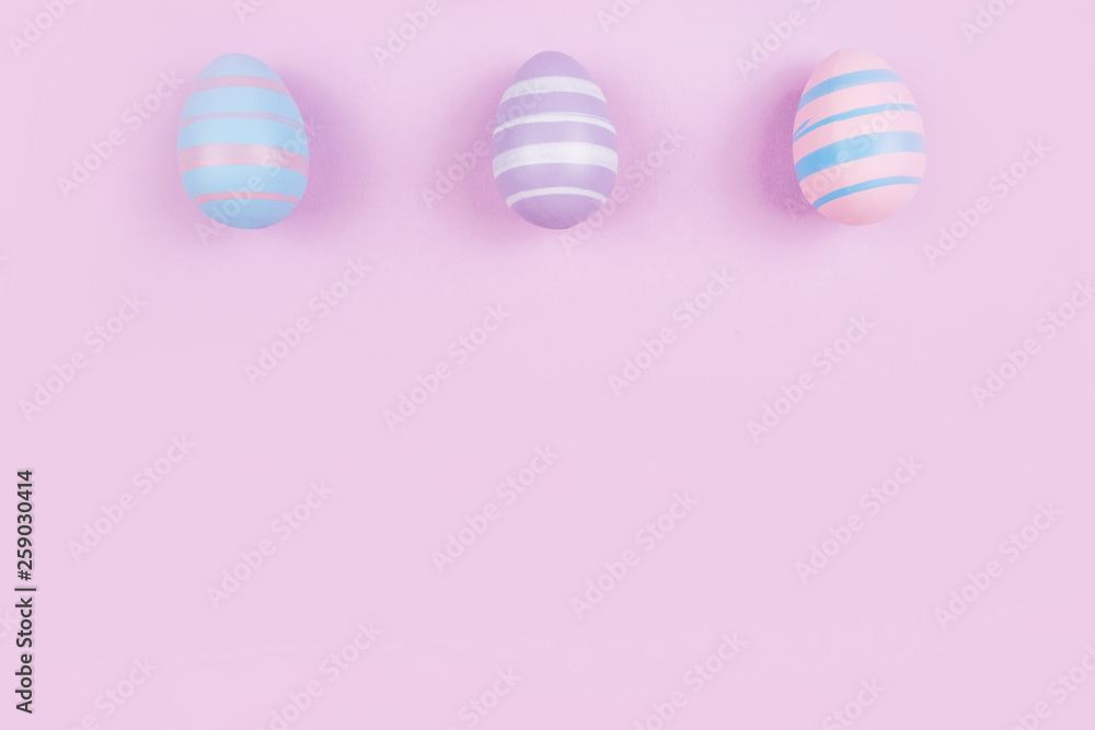 Three dyed on blue, pink and violet Easter eggs isolated on purple background. Easter theme flatlay.