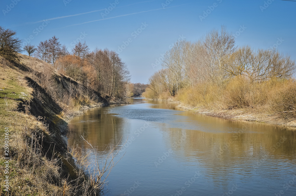 Early spring landscape on the river with blue sky. Nature awekening from winter.