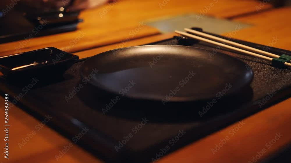 In a Japanese restaurant, a table and various traditional cutlery for food are waiting for visitors. In a Japanese restaurant, a table and various traditional cutlery for food are waiting for visitors.