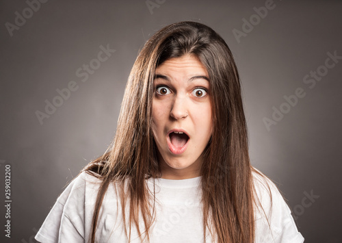 portrait of surprised young girl on a gray background