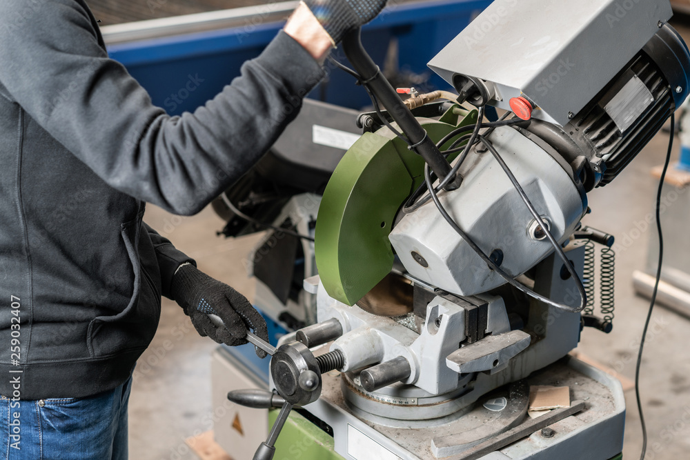 worker cuts a piece of material with a circular saw machine. Industrial engineer working on cutting a metal and steel with compound mitre saw with sharp, circular blade worker cuts a piece of material with a circular saw machine. Industrial engineer working on cutting a metal and steel with compound mitre saw with sharp, circular blade