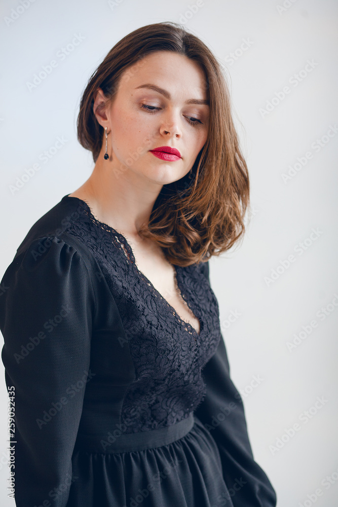 beautiful girl with red lipstick in a black dress is sad and looks down beautiful girl with red lipstick in a black dress is sad and looks down