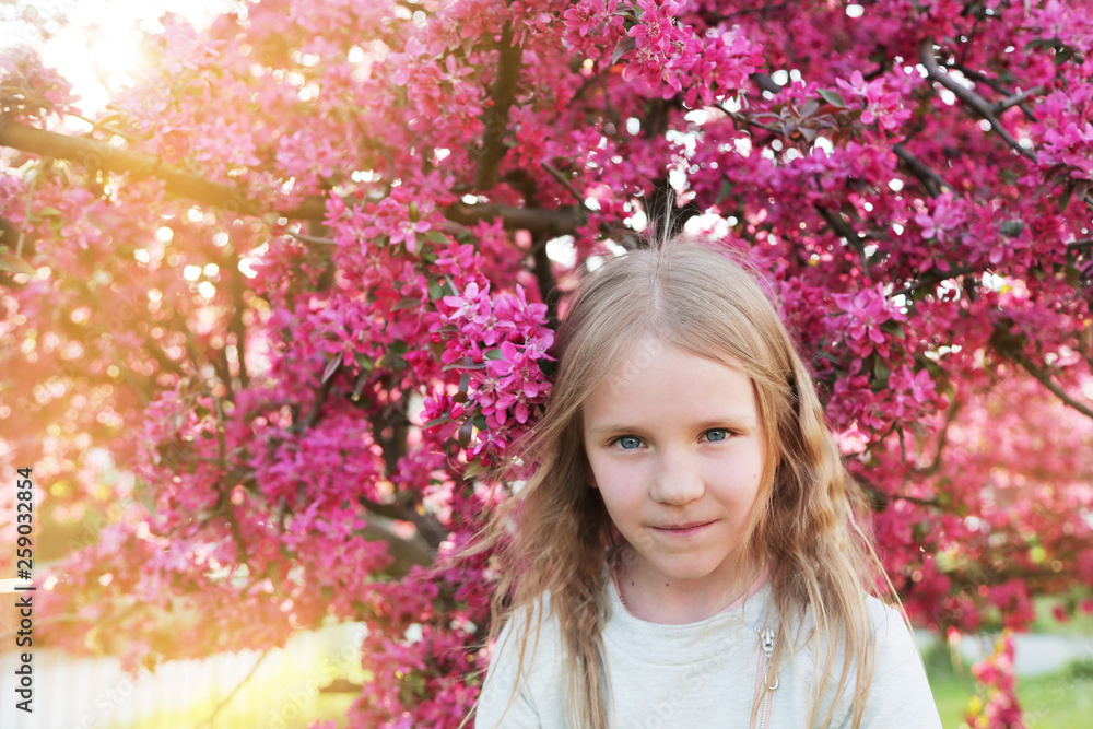 Beautiful pretty blond little girl smelling flowers in blooming sakura garden. Beautiful pretty blond little girl smelling flowers in blooming sakura garden.