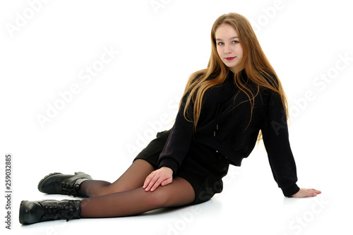 A teenage girl is sitting on the floor.