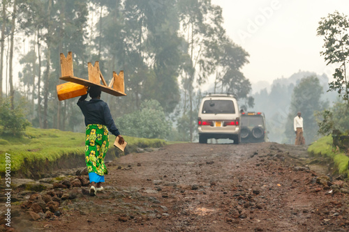 Rwandan woman in colorful traditional cloth walikung and carrying bench on her head, Kigali, Rwanda photo