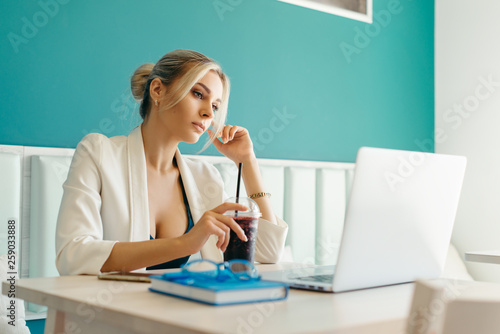 Beautiful girl working out a plan of the project and concept. Girl paints a website design on a laptop. student prints a message on the phone in the messenger. Development. Digital marketing