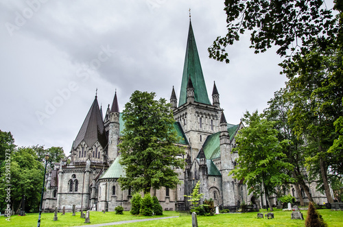 Nidaros cathedral in Trondheim, Norway, with green trees and garden in the foreground