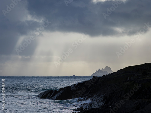 a view of the wild atlantic way off the coast of the ring of kerry in ireland showing skellig michael and surrounding islands in beautiful strong light with cloudy skies 