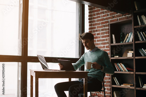 Young man drawing template for the web site associated with digital marketing, current trends and tendencies of UX / UI design. Businessman who rules his company remotely, like a freelancer © Cressida studio